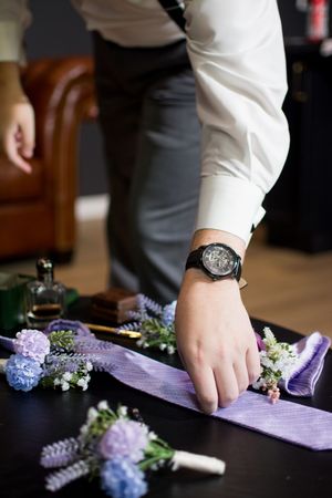 Purple ribbons and floral decorations being arranged on a dark surface for a wedding event.