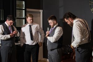 Group of groomsmen in formal attire gathered indoors before wedding ceremony.