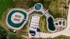 Aerial panoramic view of circular swimming pools and landscaped grounds at a luxury resort property.
