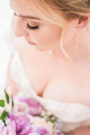 Close up of a wedding bouquet with delicate purple and pink flowers against a light background.