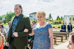 Wedding processional on wooden benches at an outdoor venue.