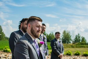 Wedding party standing outdoors under blue sky with purple accents.
