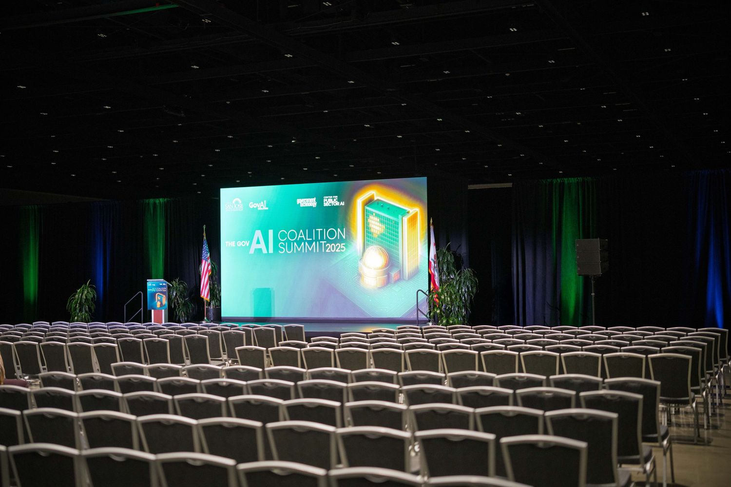 Chairs face a stage with colorful lighting and curtains in a modern theater auditorium for big tech event.