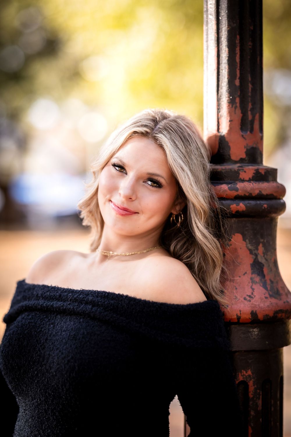 A series of four portrait shots showing a woman in a black off-shoulder top posing against a rustic metal pole outdoors.