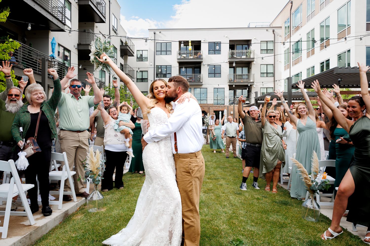 Wedding party cheering outside Cambium Place in Missoula, with Matt and Maggie standing center surrounded by family and friends.