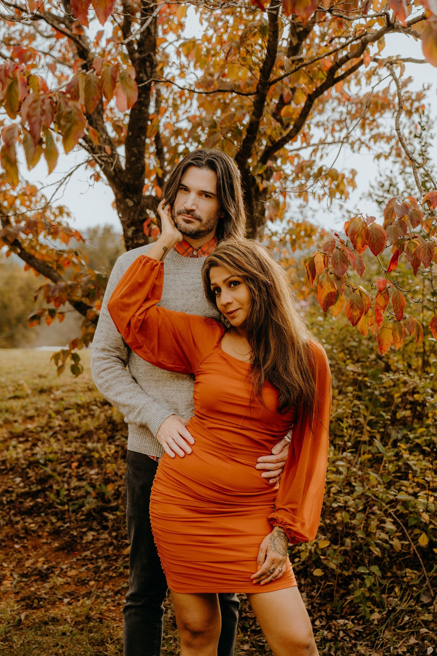 Romantic autumn photoshoot in a rustic setting with orange dress and grey sweater.