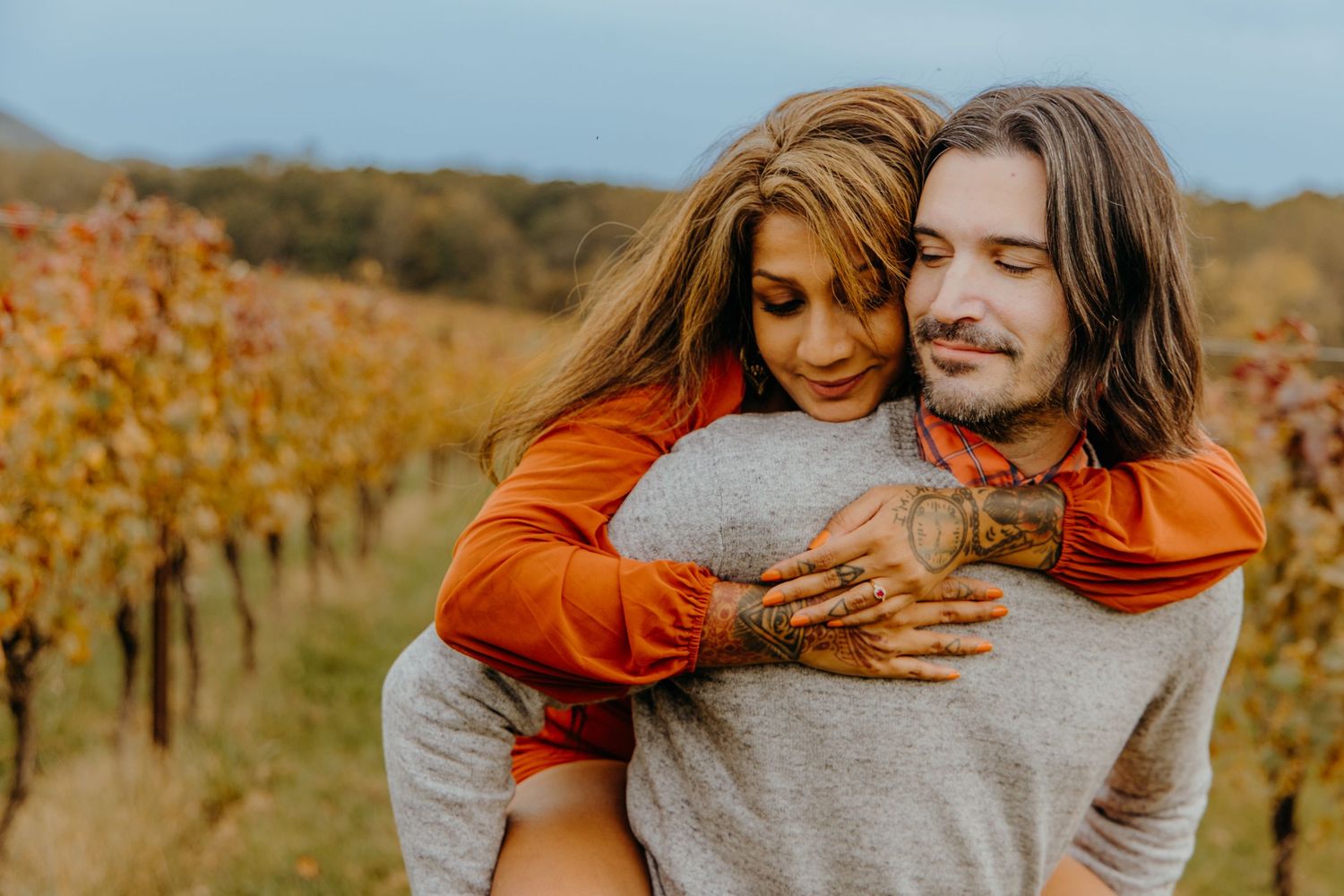 Tender embrace captured in warm autumn light with vineyard backdrop.