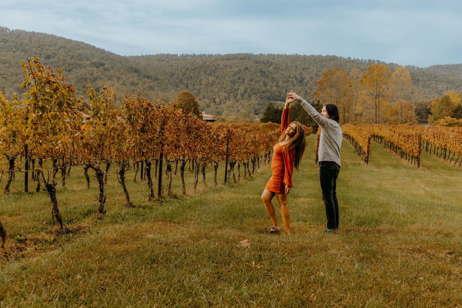 Dancing together in vineyard with autumn colors and mountain landscape.