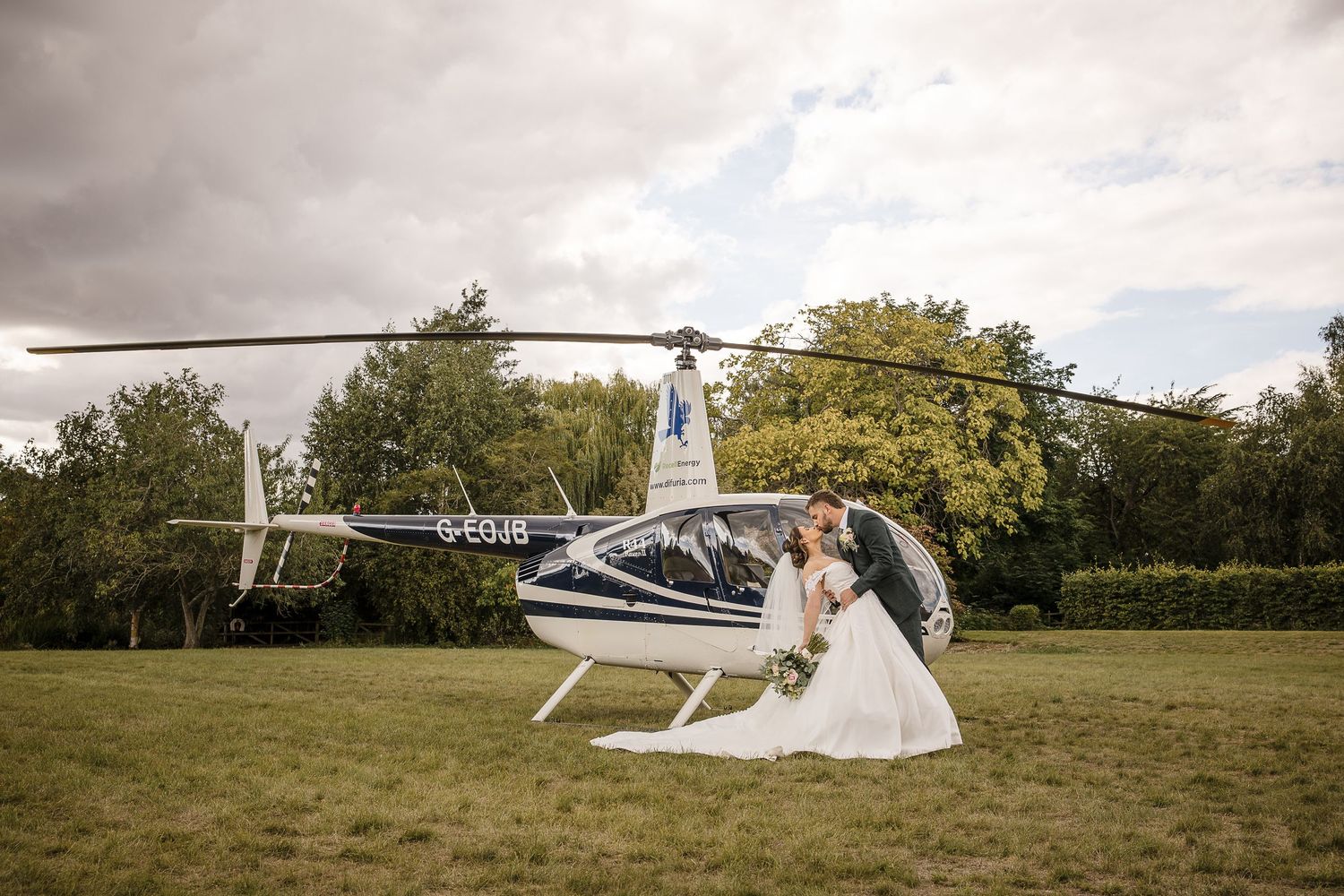 Bride & Groom kiss in front of the helicopter that flew them to Hodsock Priory