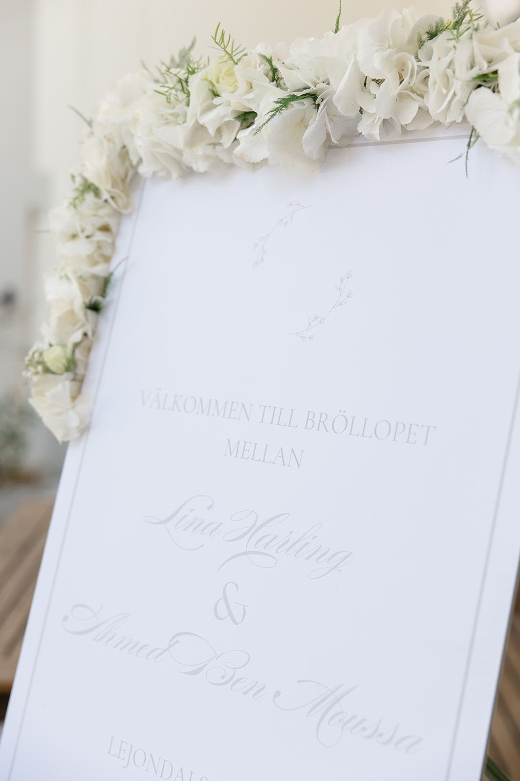 Elegant crystal chandeliers illuminate a grand room with ornate wooden doors and a red carpet through open doorways.