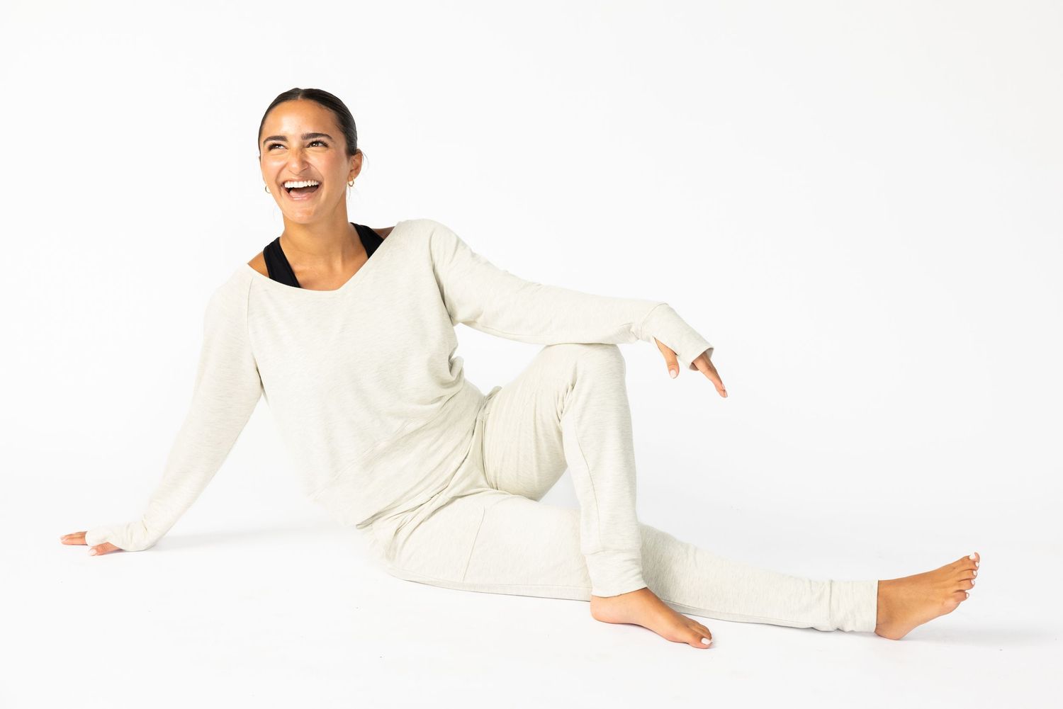 Athletic figure in black sports bra poses against brown backdrop in dynamic fashion photoshoot series.