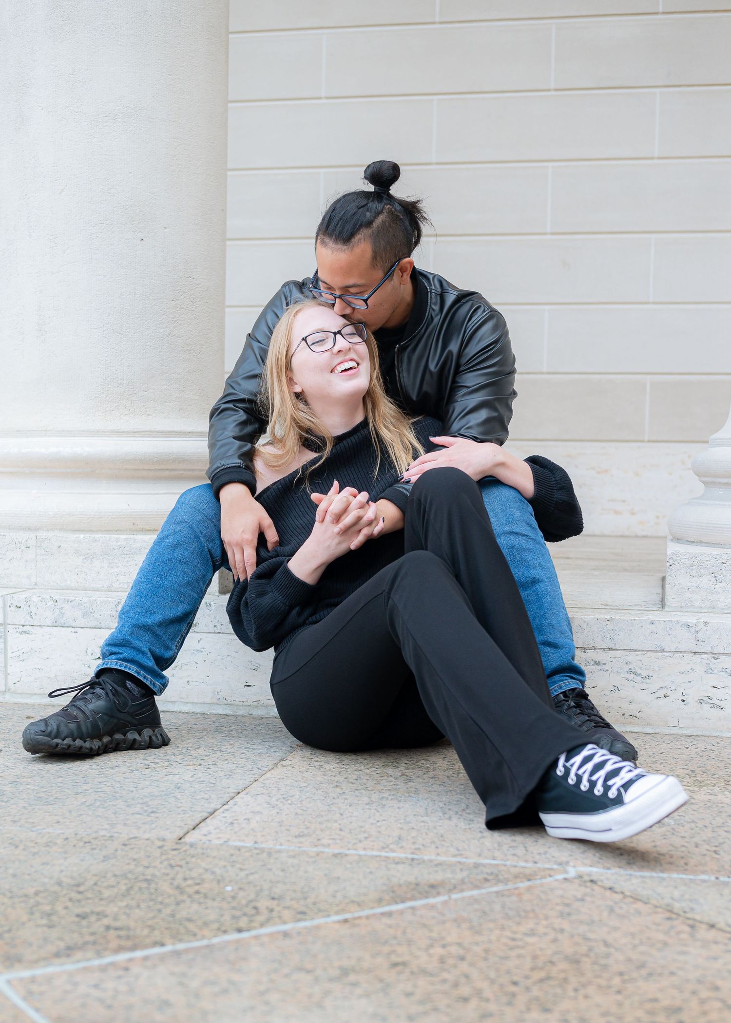 A couple shares an intimate moment while sitting on stone steps together.
