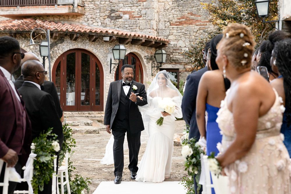 Wedding party walking through a rustic stone courtyard during a celebration.