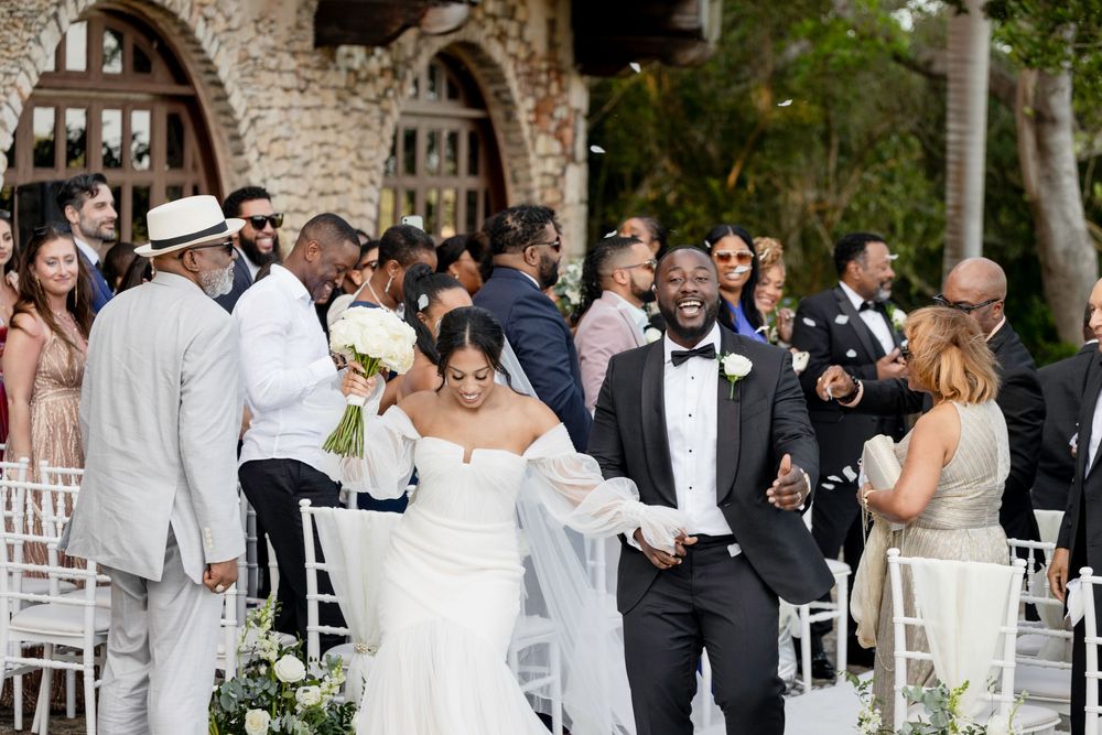 Wedding guests mingle and socialize during an outdoor reception at an elegant stone venue.