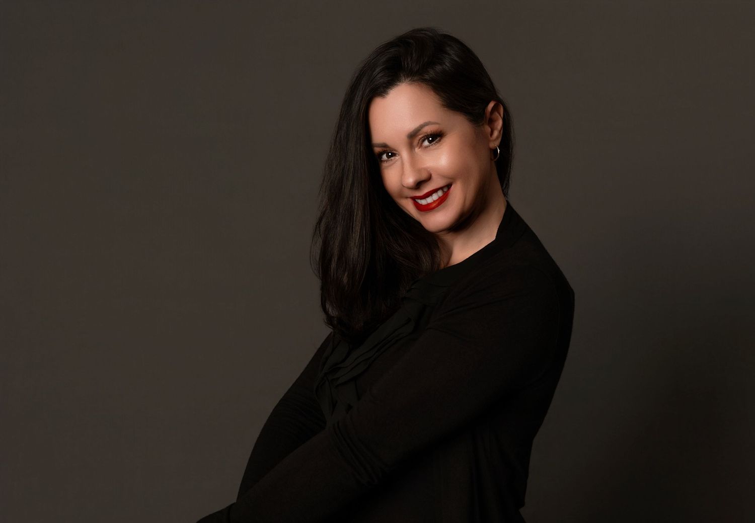 A figure in a black sweater poses against a dark background in a dramatic portrait series.