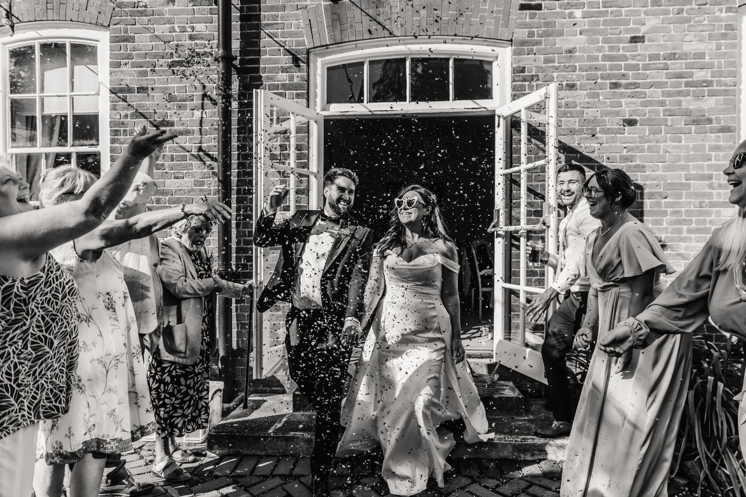 Confettibshot of a Bride and Groom wearing sunglasses at the Hotel Du Vin in Winchester. From a candid wedding photographer.