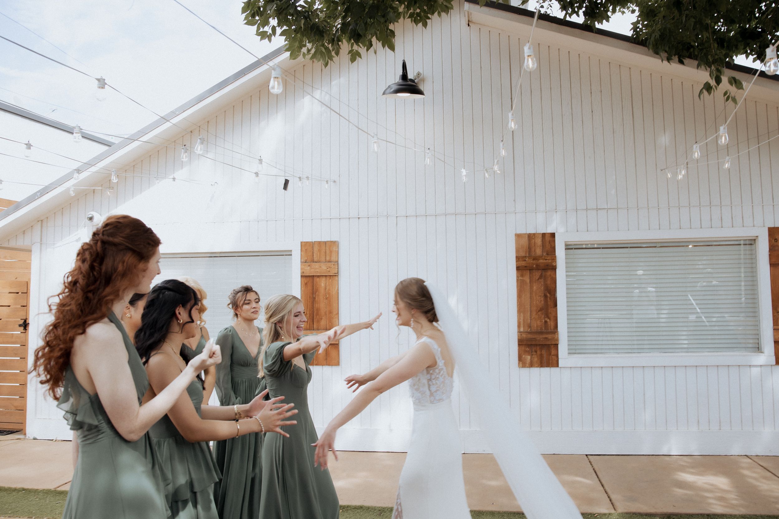 A group celebrates joyfully in a bright white room with wooden accents and decorative lanterns hanging overhead.
