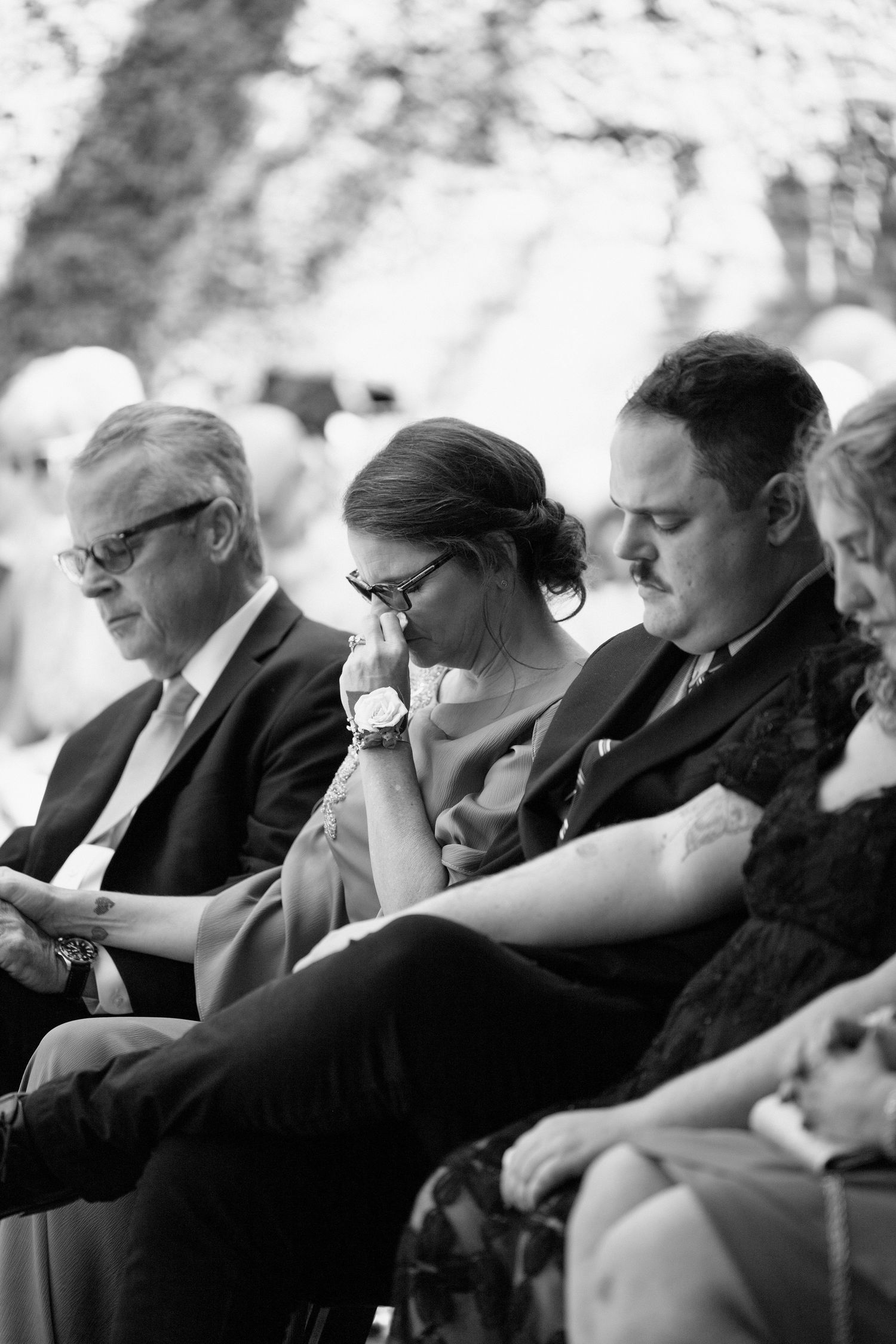 Black and white photograph showing a row of people sitting and crying at what appears to be a funeral or memorial service.