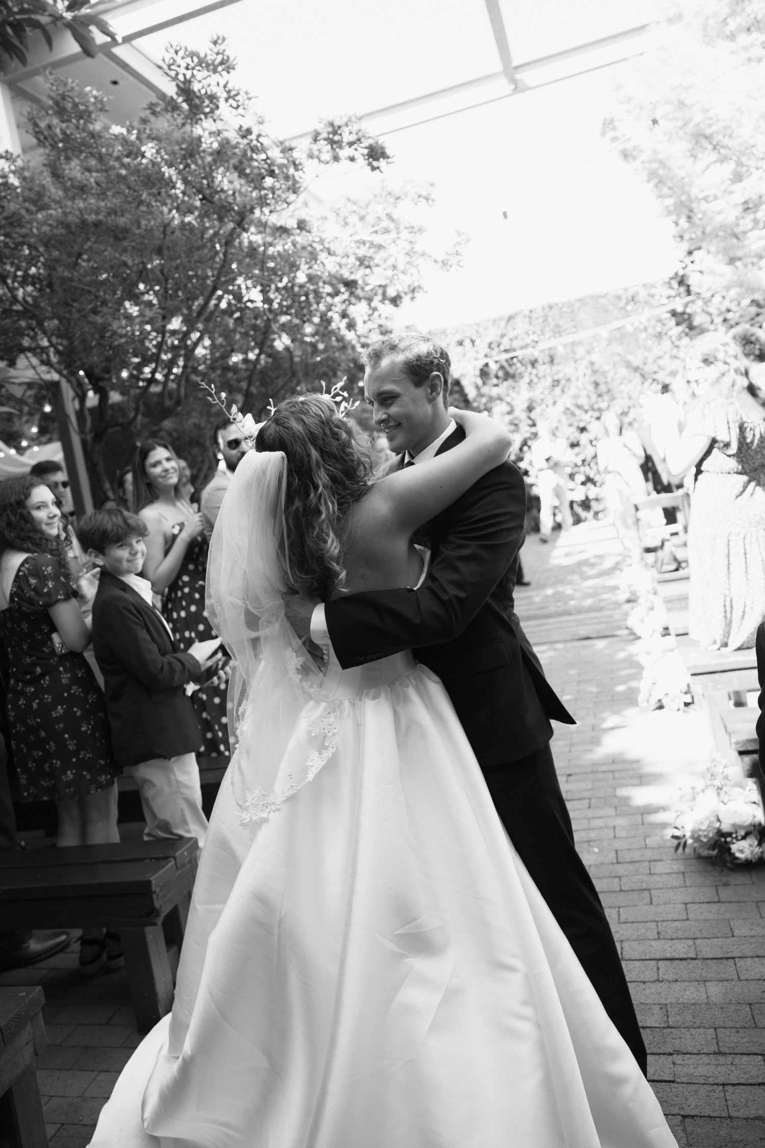 A sequence of wedding photos showing a romantic dip kiss between newlyweds on a brick patio surrounded by guests.