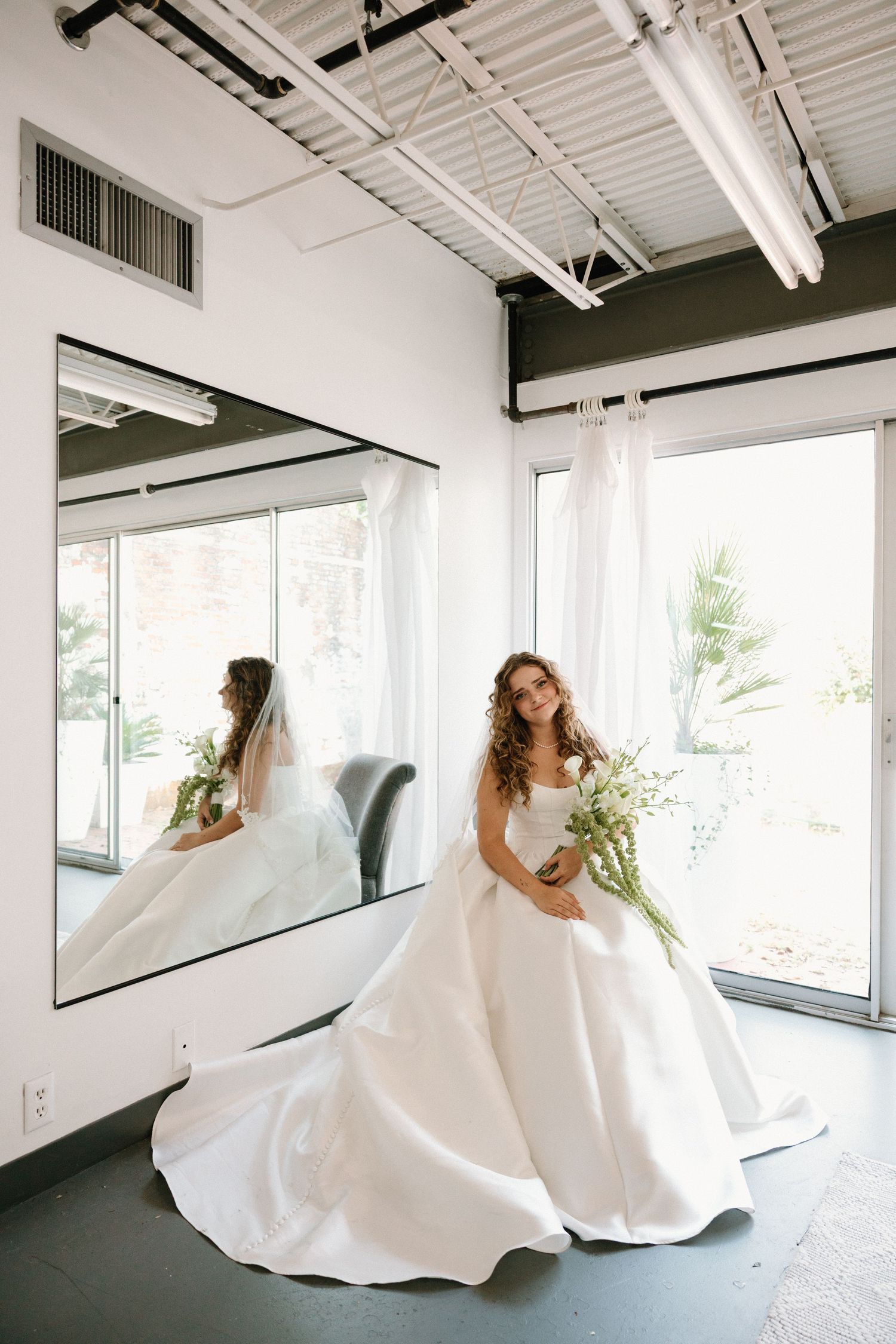 A sequence of four photos showing a bride in a flowing white wedding dress twirling and moving in an industrial space.