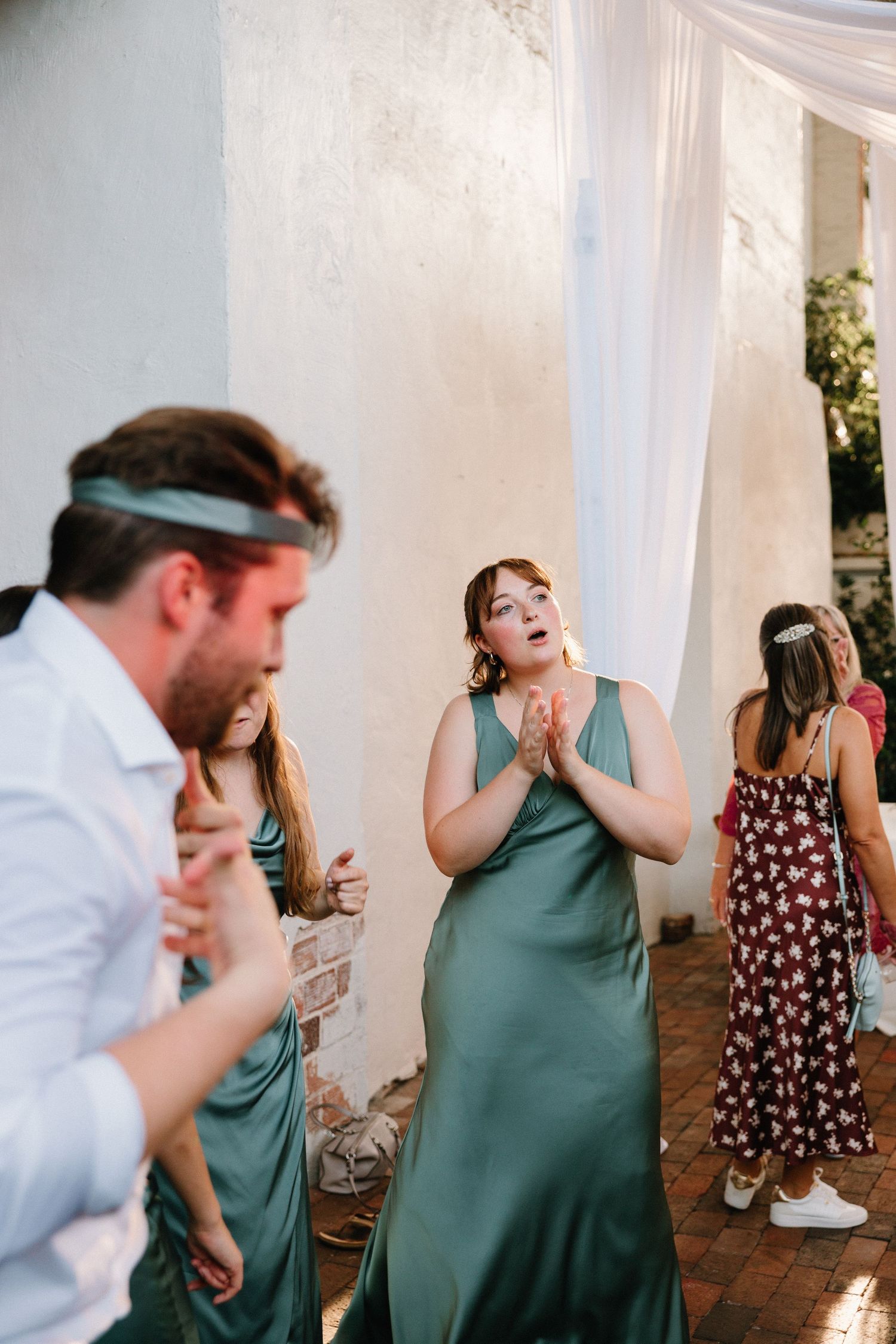 A sequence of candid dance floor moments showing people enjoying themselves at a celebration with white drapes in background.