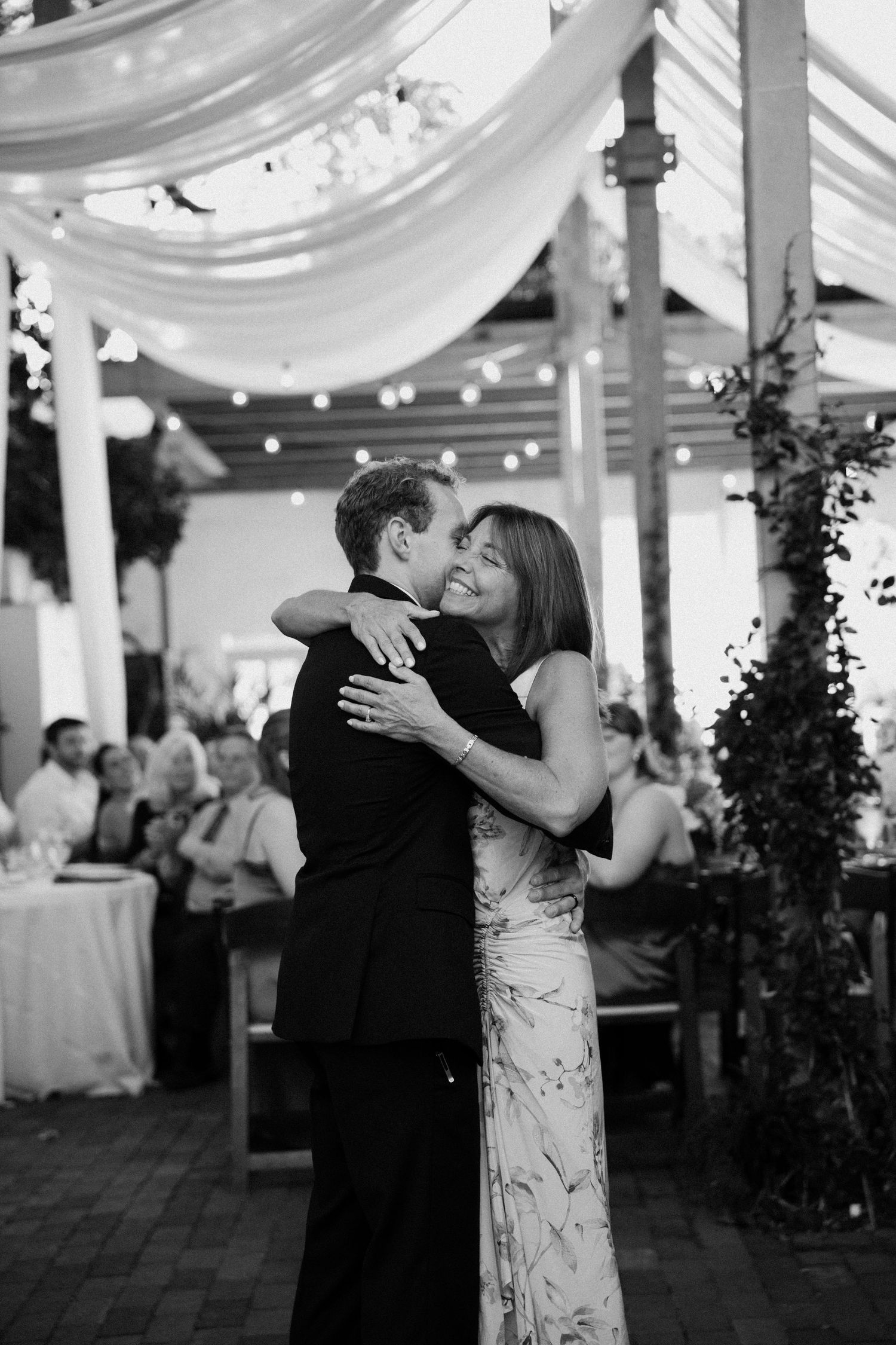 A romantic dance sequence at a wedding reception under draped white fabric and string lights.