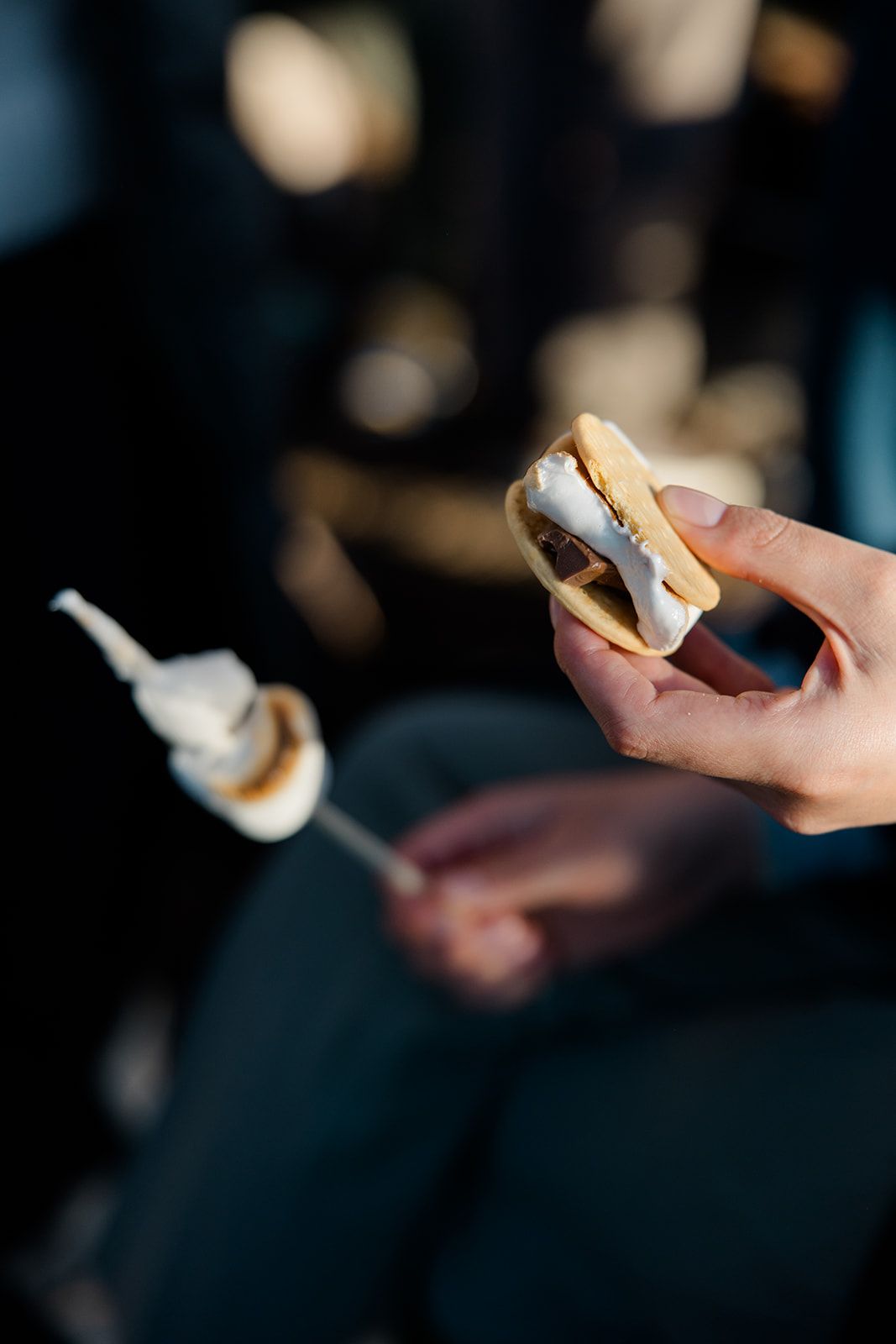 Hand holding a smartphone in dark lighting with blurred bokeh background effects.