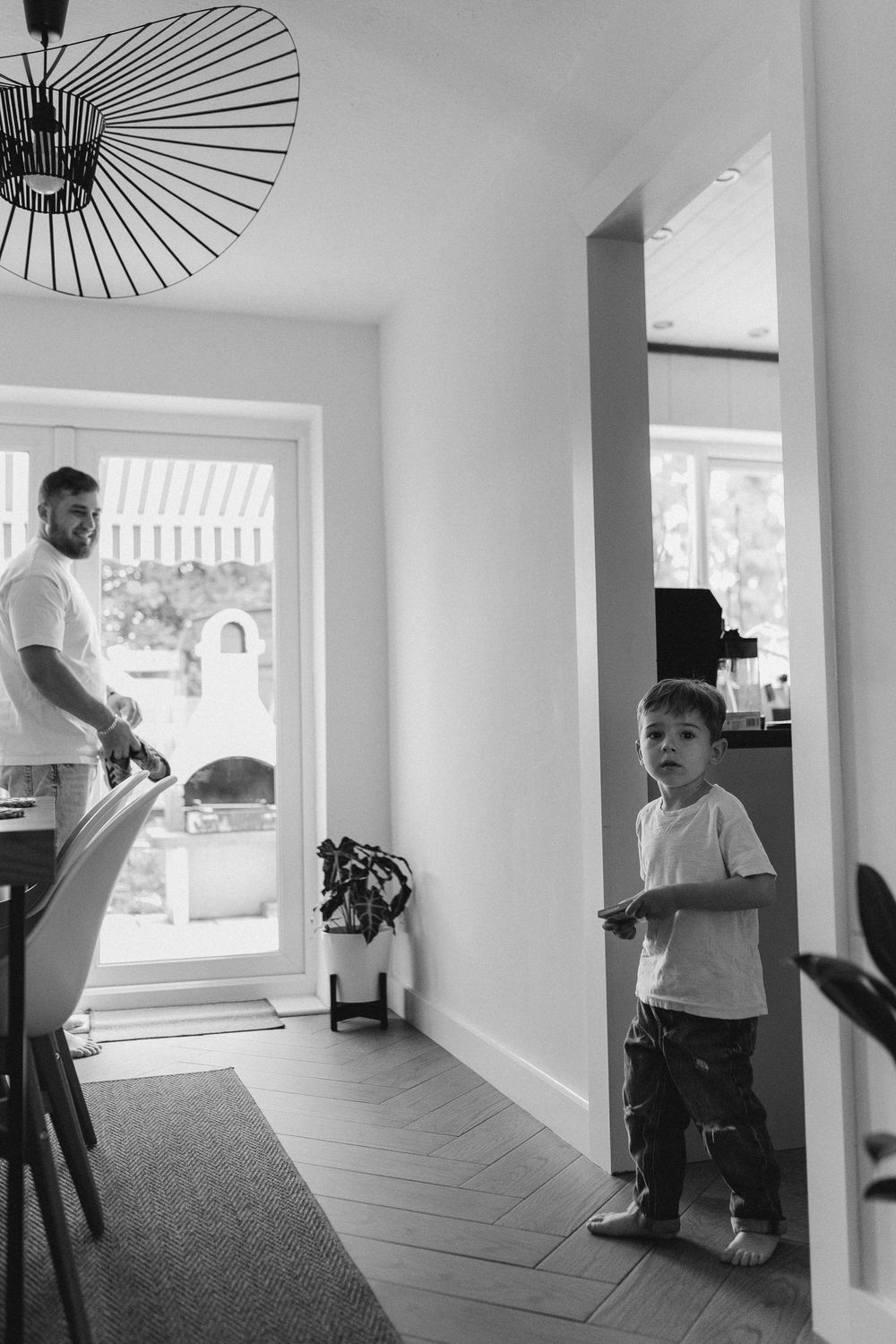 A series of black and white photos showing playful movement in a bright hallway with sunlit windows.