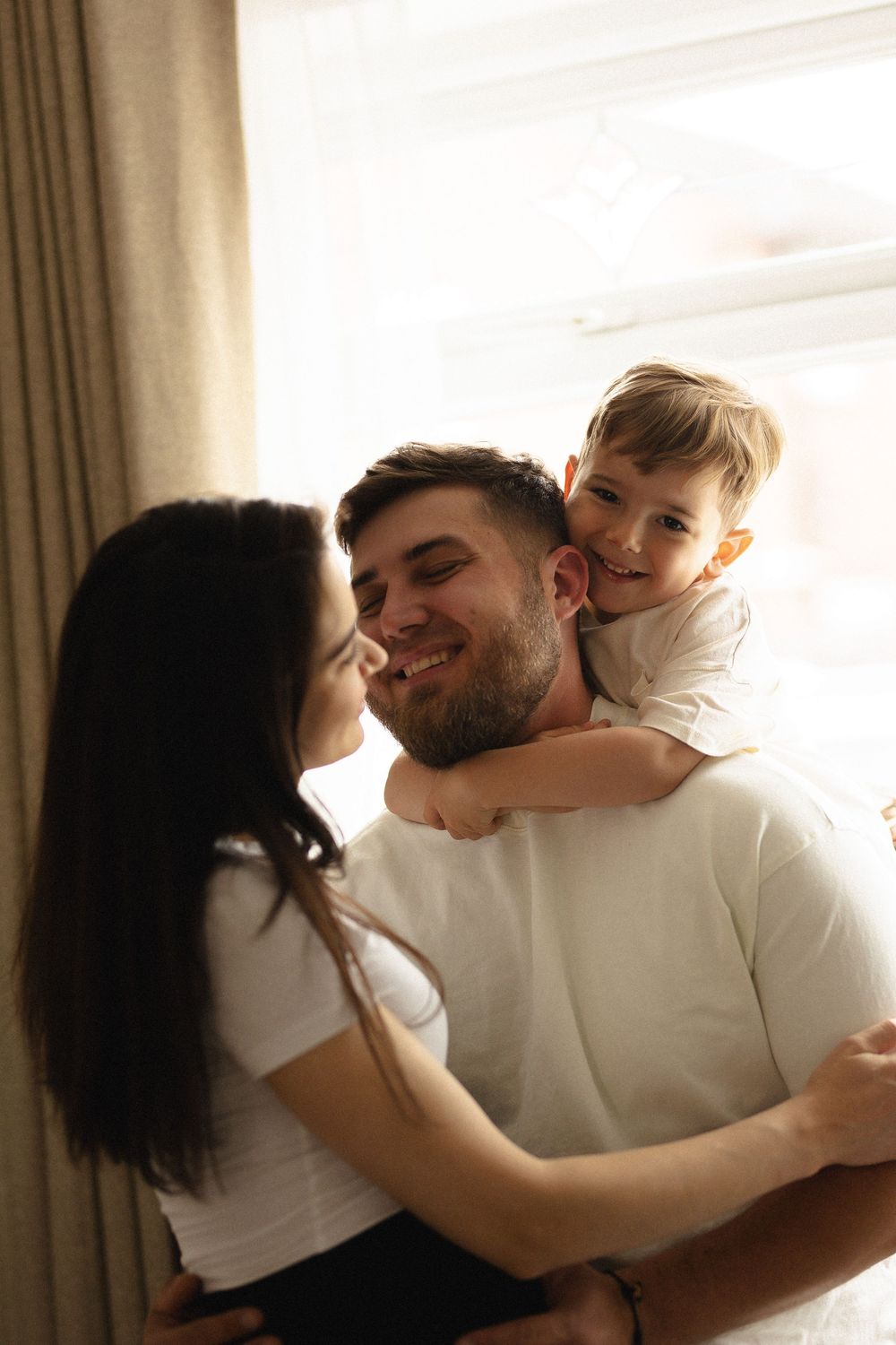 A sequence of intimate family moments captured in warm lighting against curtained windows.