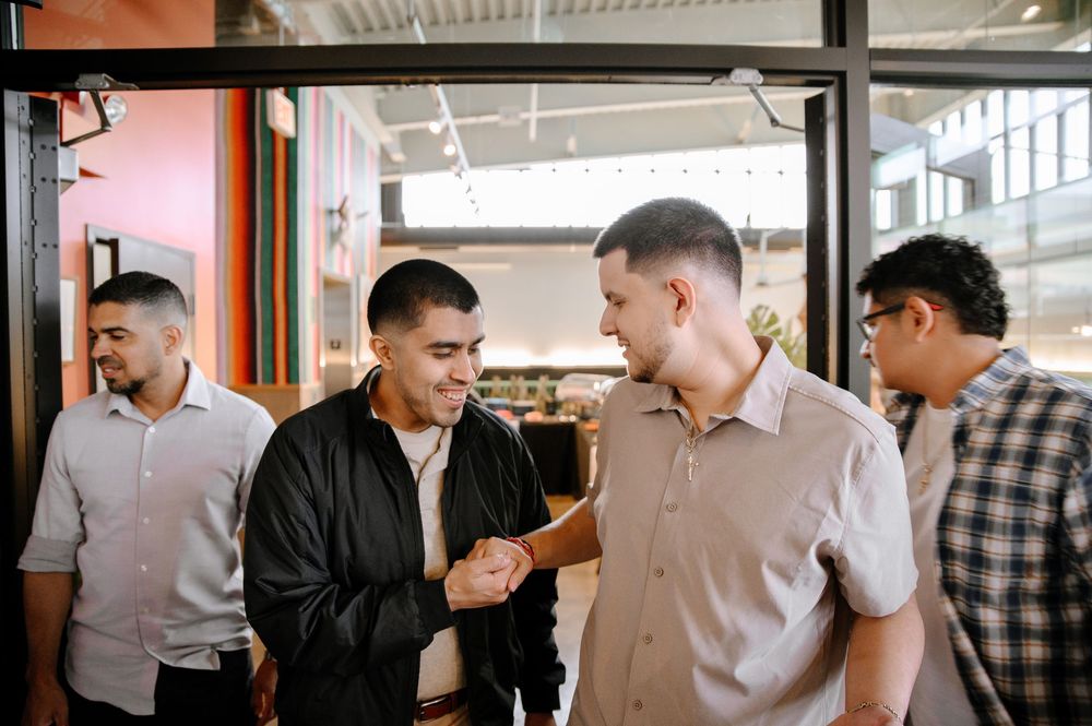 A group of people having a casual conversation in an office hallway while standing in a line formation.
