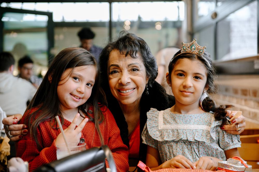 Group of friends enjoying a meal together at a restaurant, smiling and laughing while sitting at a table.