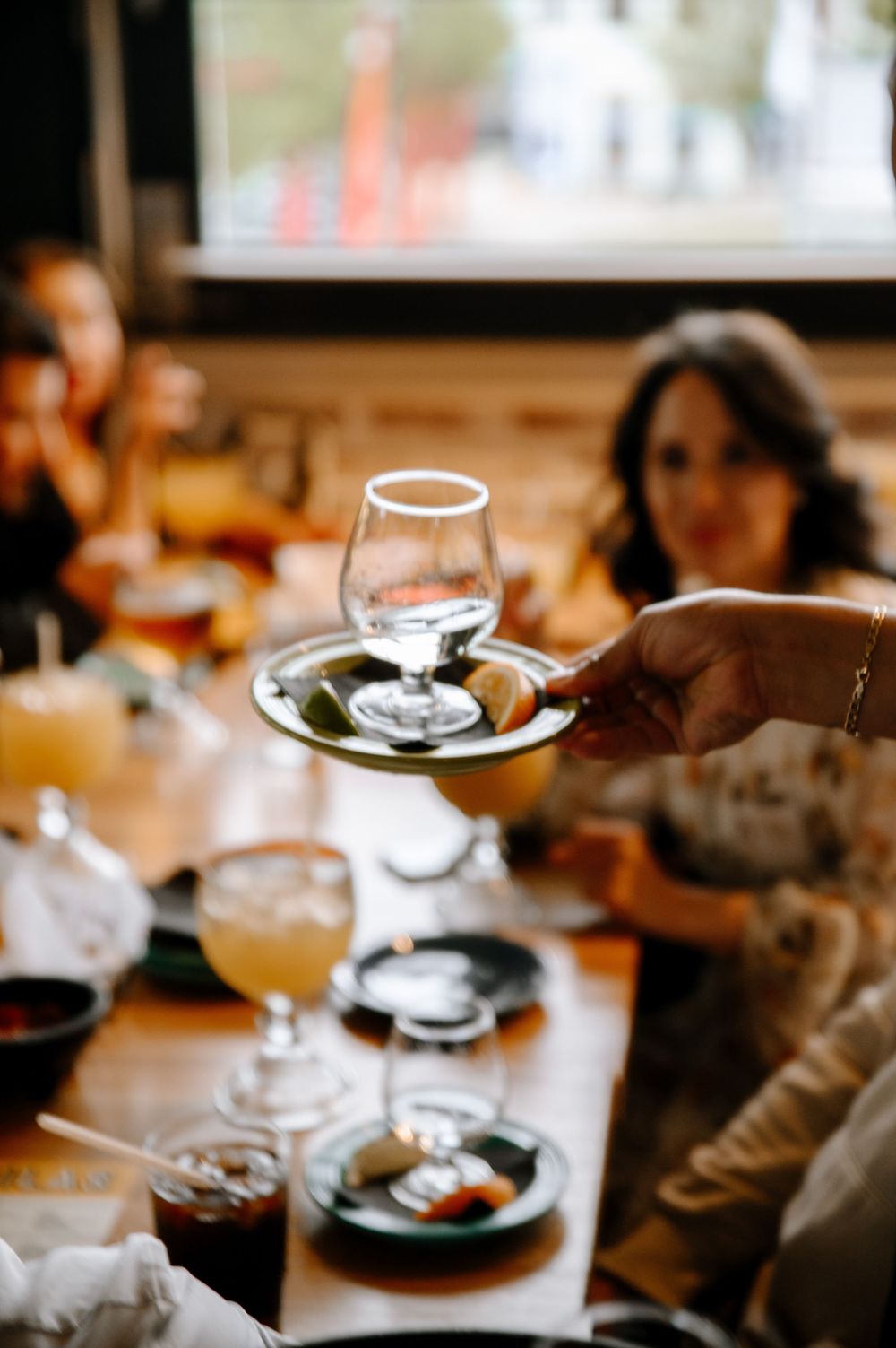 Wine glasses and plates sit on a wooden table in a warmly lit restaurant setting.