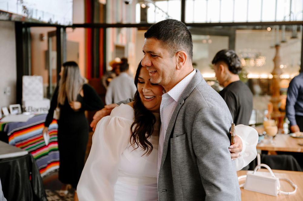 A group celebrates together in a modern restaurant with exposed brick walls and large windows.