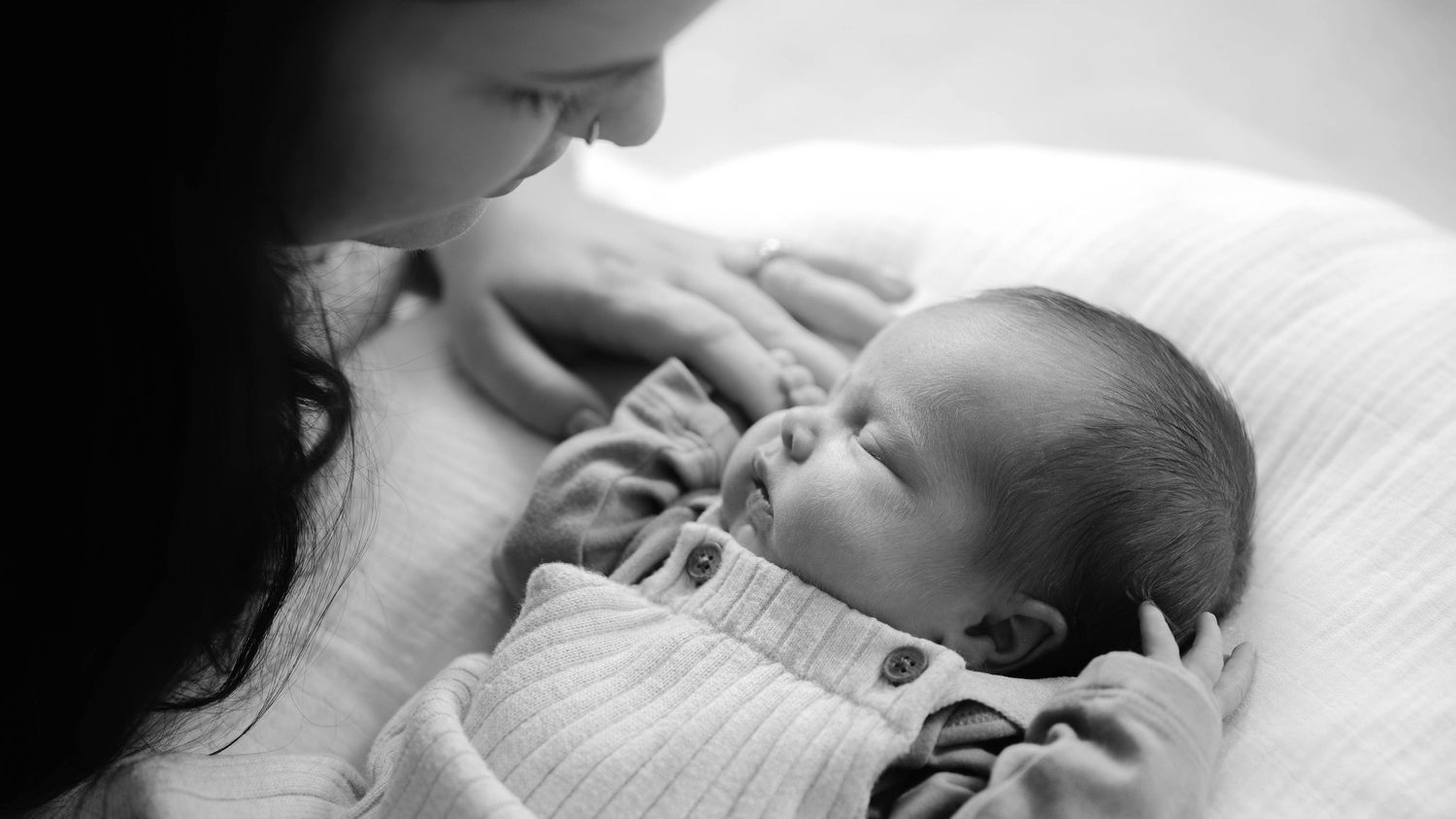 A series of black and white photos showing a sleeping baby in various peaceful poses.