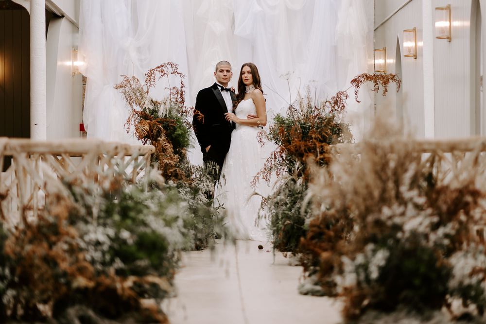 A romantic wedding venue with dried floral arrangements and white fabric draping from the ceiling.