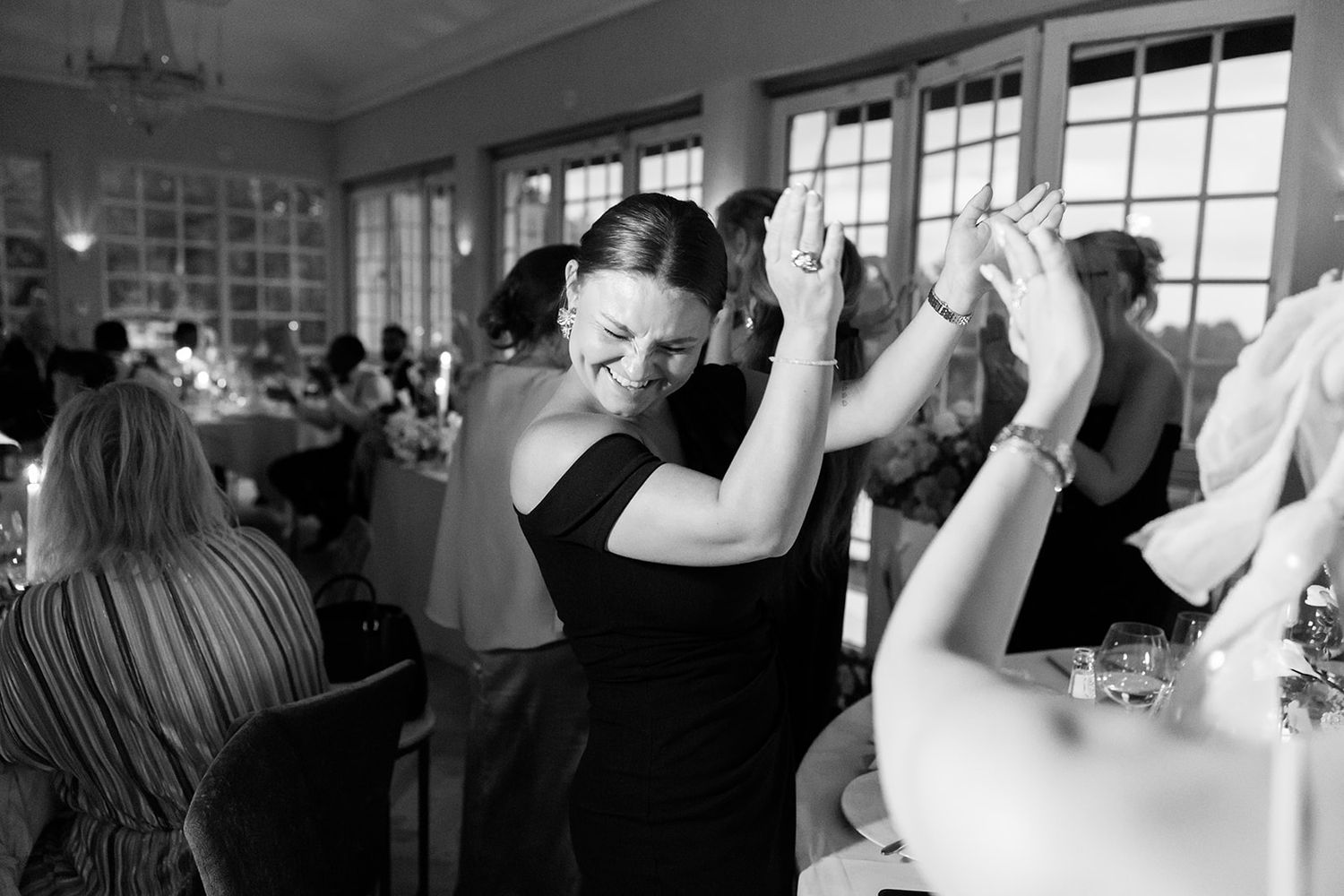 A tender moment captured in black and white as makeup is being applied during wedding preparations by a window.