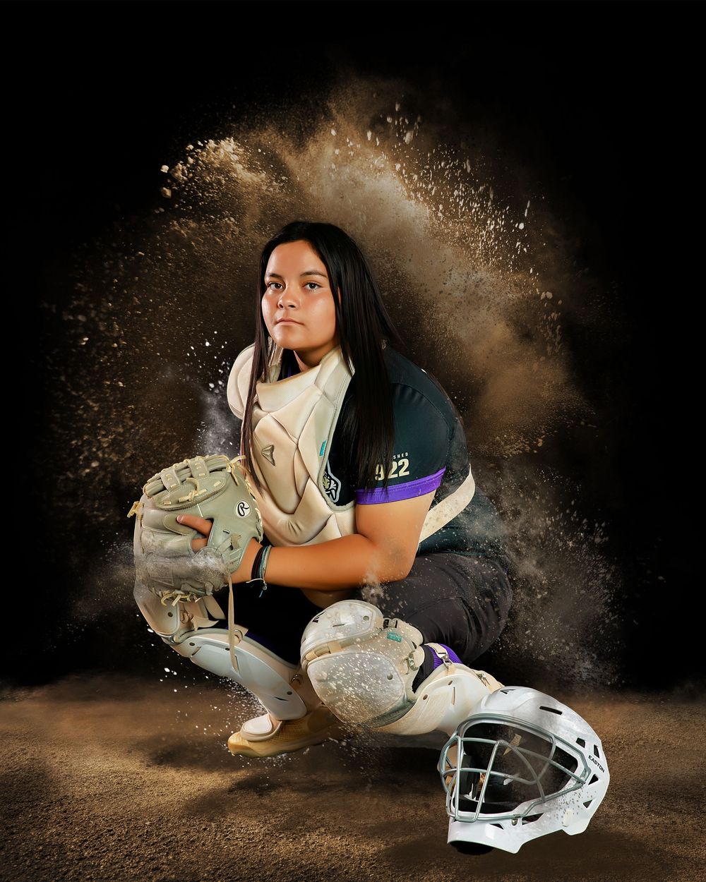 Dramatic sports portrait with softball gear and equipment against dark background with explosive powder effect.