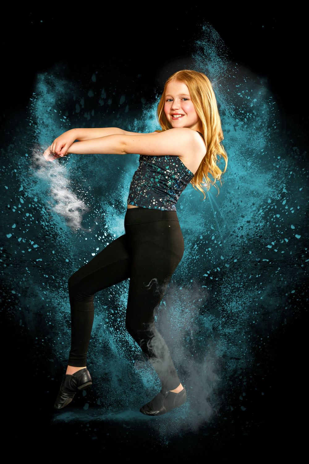 A dancer performs dynamic movements against a dark background with dramatic turquoise powder effects creating an ethereal scene.