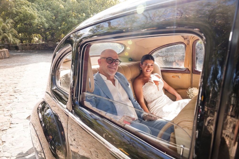 A collection of vintage cars and their passengers shown through car windows at a classic automobile event.