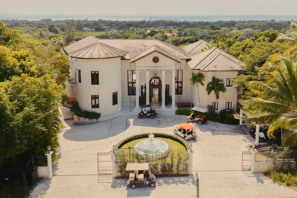 Aerial view of a luxurious Mediterranean-style estate with white buildings and manicured grounds.