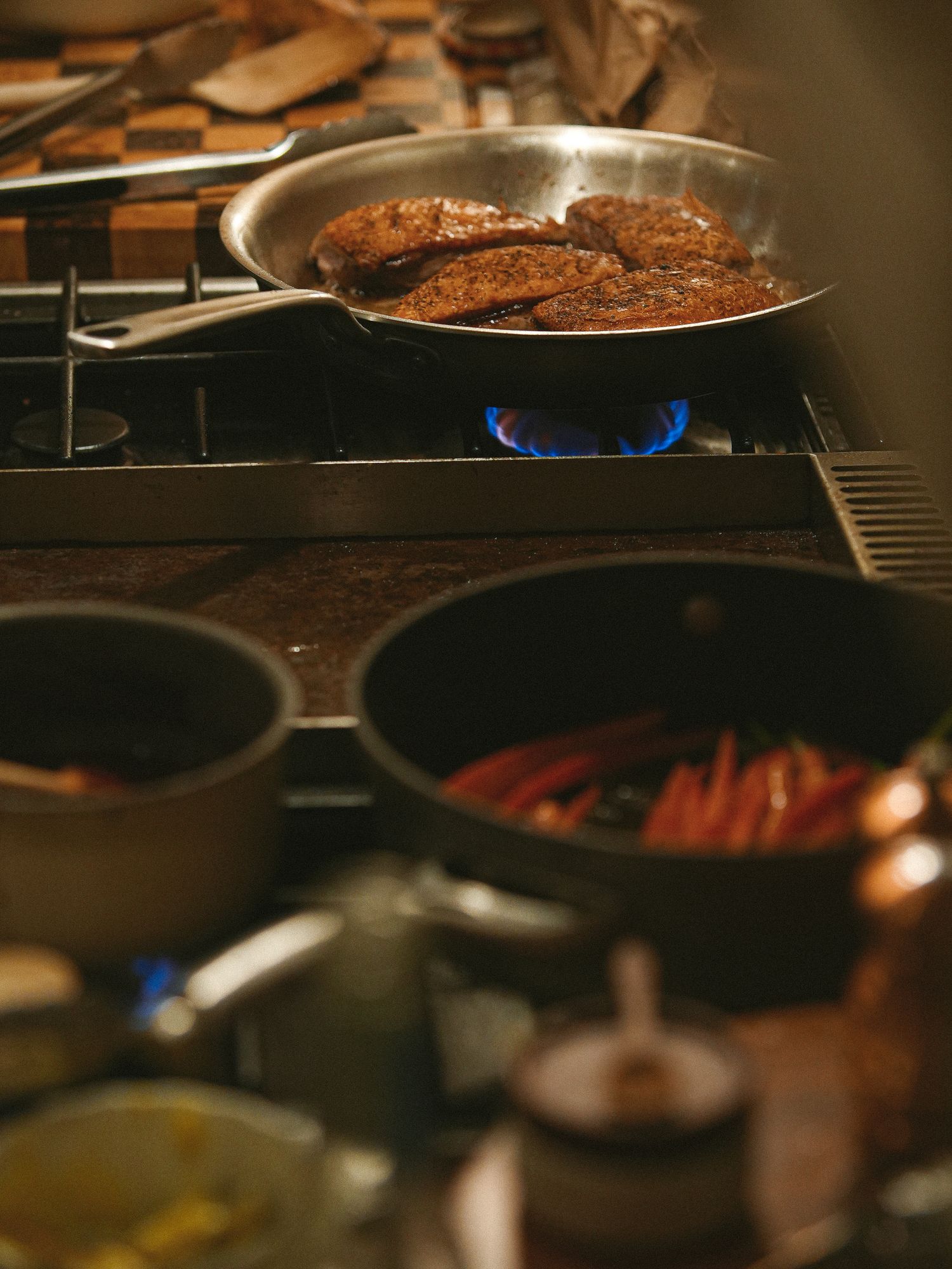 A cast iron pan cooking on a gas stove burner with blue flames visible beneath.