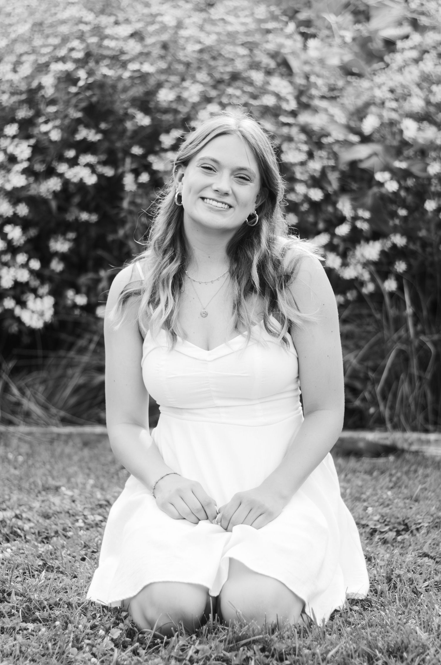 A black and white portrait of a young woman in a flower field