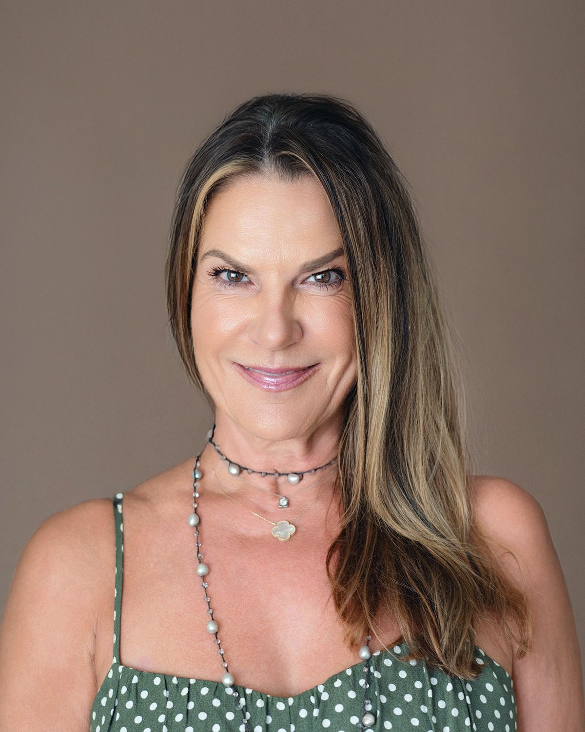 I 45 year old woman in a green tank top posing for camera for a headshot