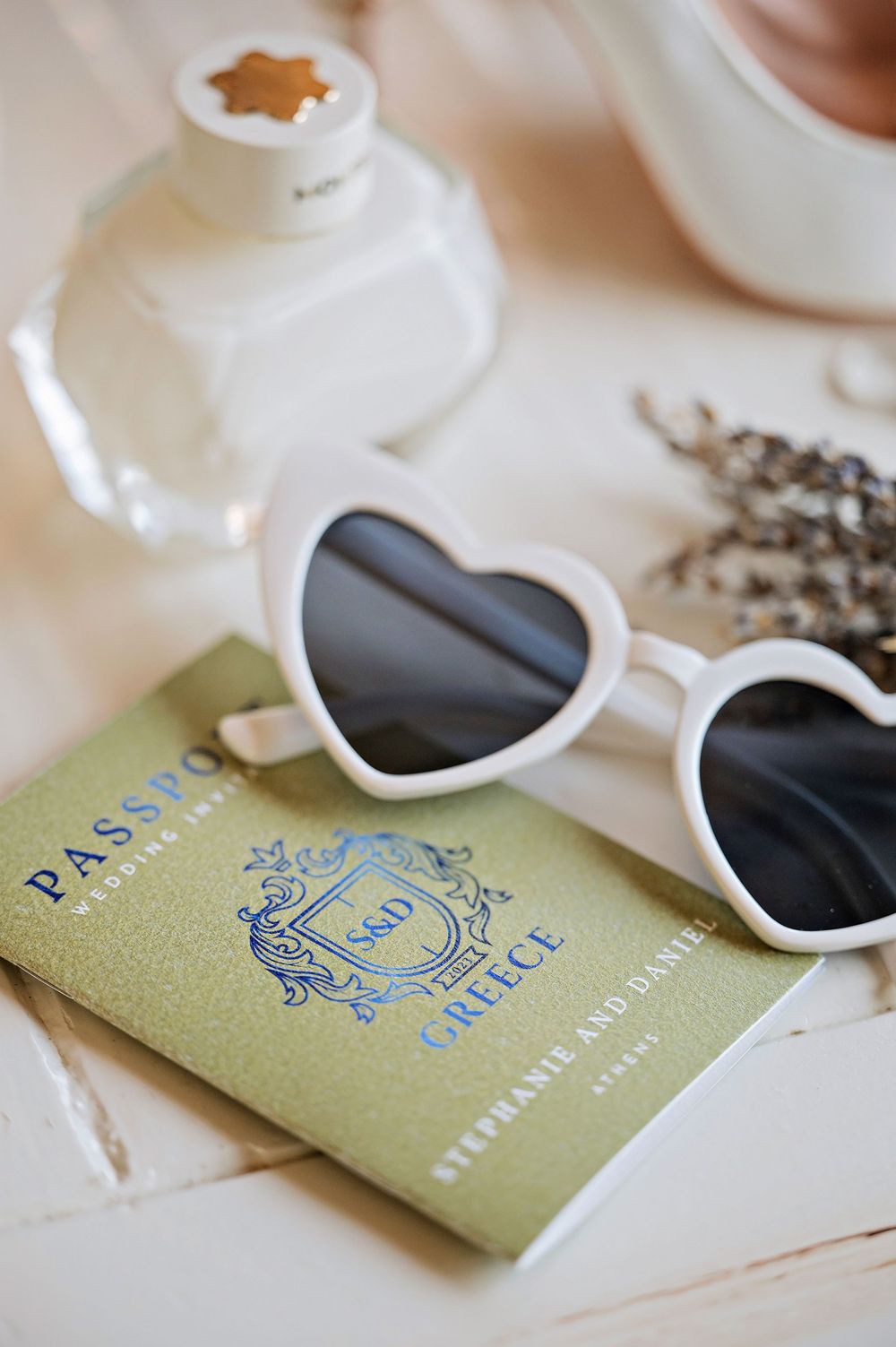 Heart-shaped sunglasses resting on a vintage-style passport with dried lavender.