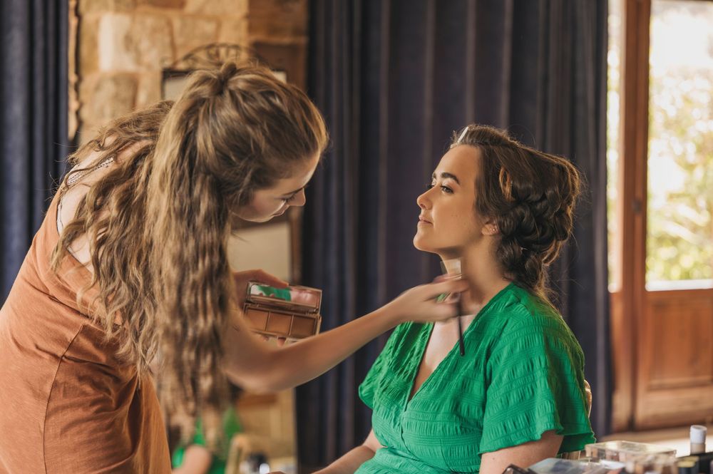 Wedding day preparations showing makeup application in a room with natural lighting.
