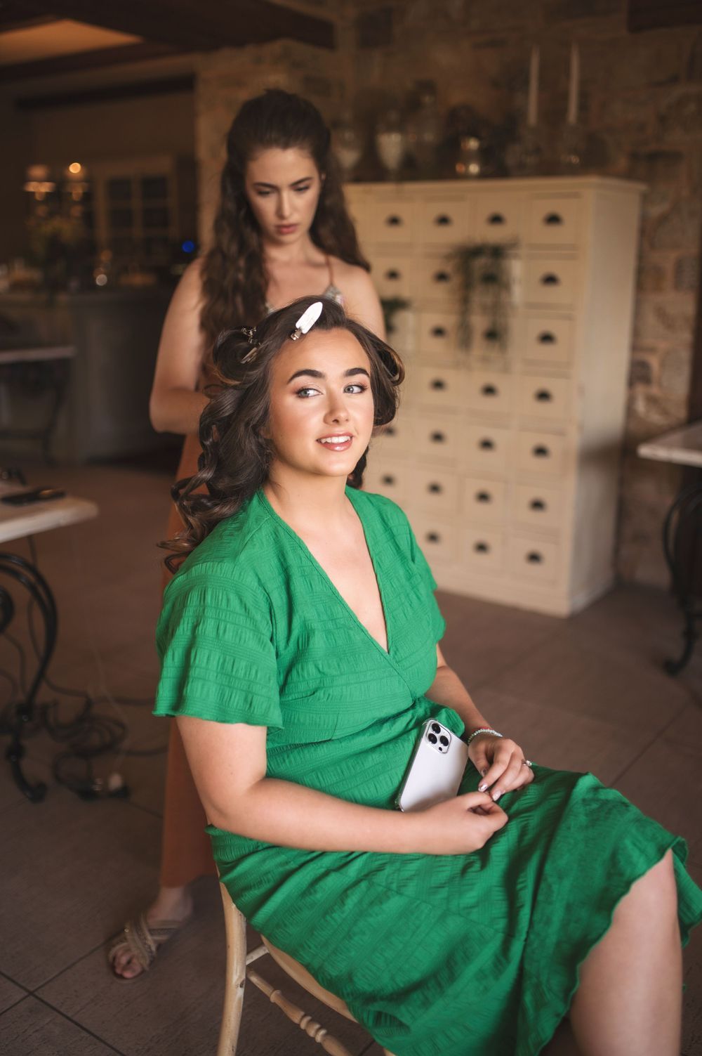 Final touches of wedding hair styling in a rustic venue with vintage furniture.