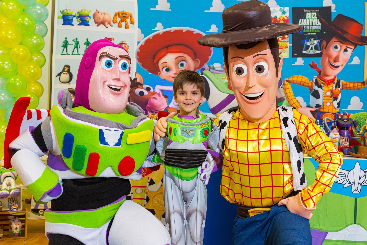 Buzz Lightyear and Woody characters pose with a young visitor at a colorful Disney theme park attraction.