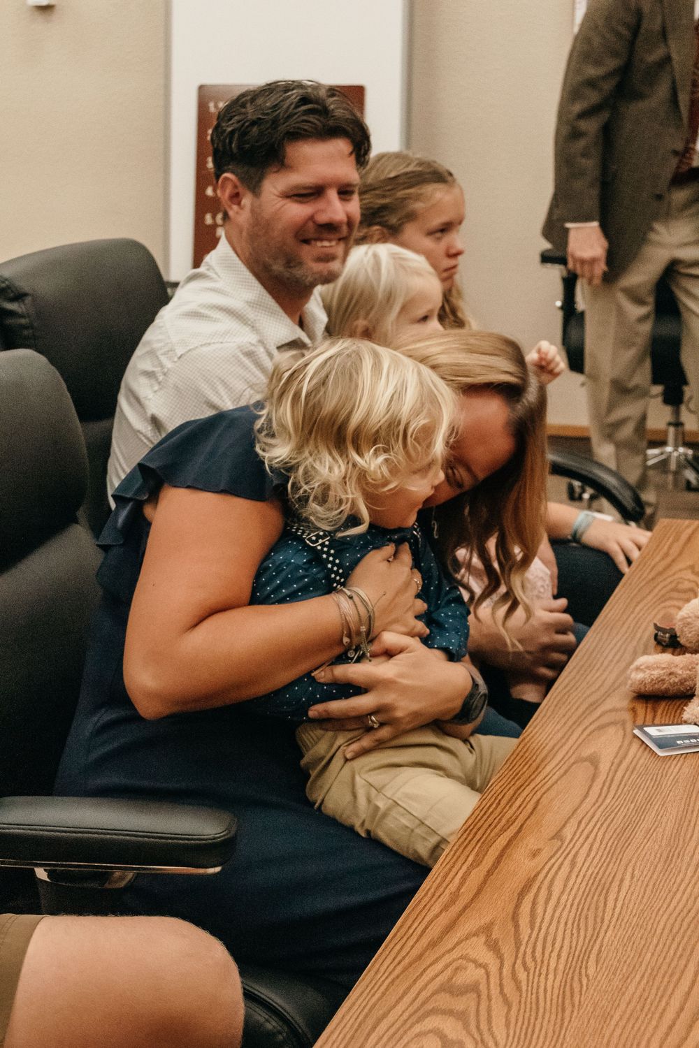 A family sits together at a wooden table in a cheerful and intimate moment.