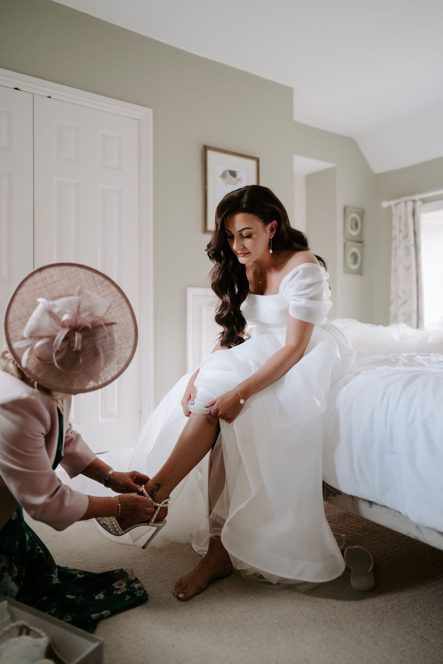brides mum helping bride put on shoes during bridal prep at the new inn cirencester