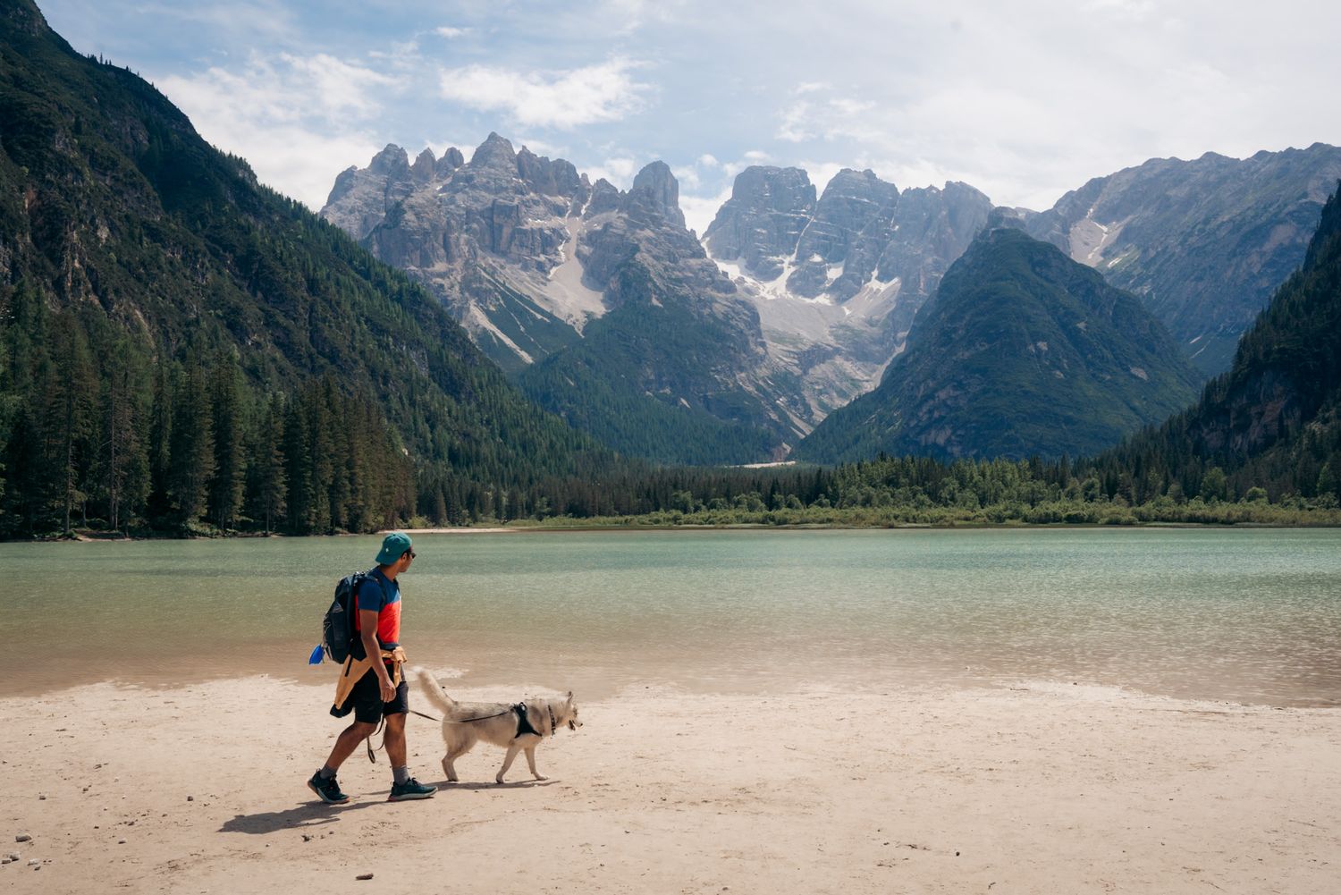 randonneur et son chien devant le lago di landro dans les dolomites